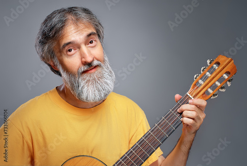 Aged man with a guitar on grey background photo
