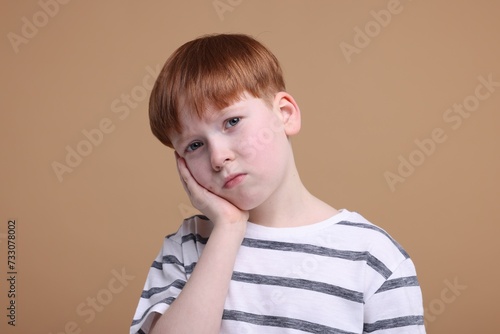 Portrait of sad little boy on beige background