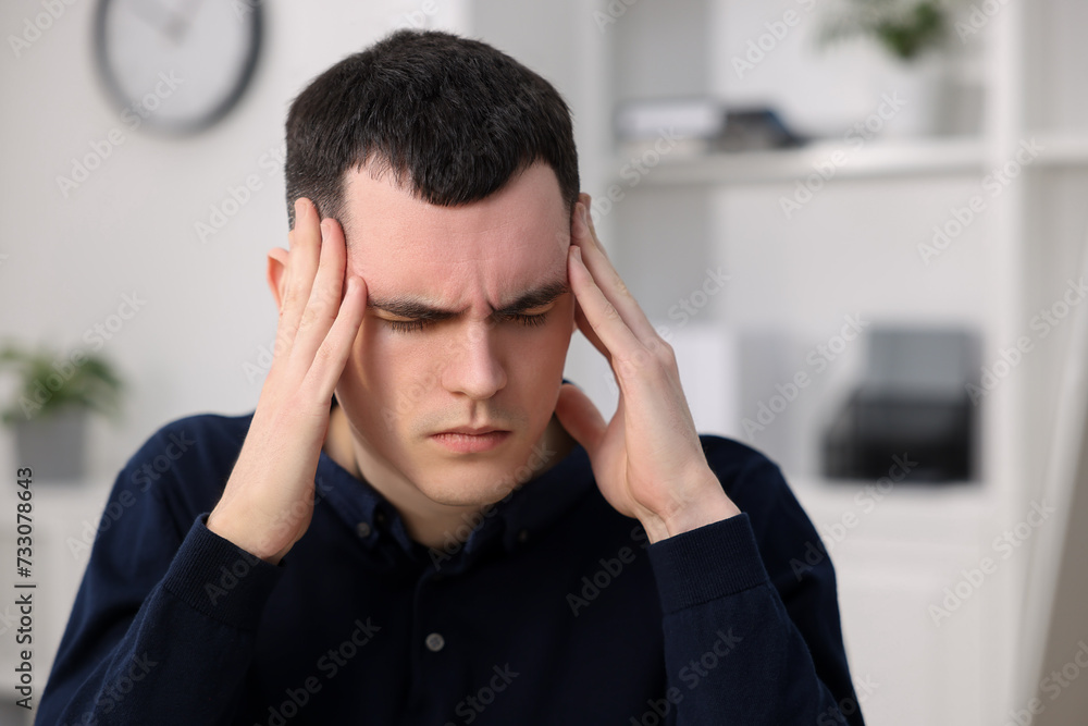Young man suffering from headache in office, space for text Young man suffering from headache in office, space for text