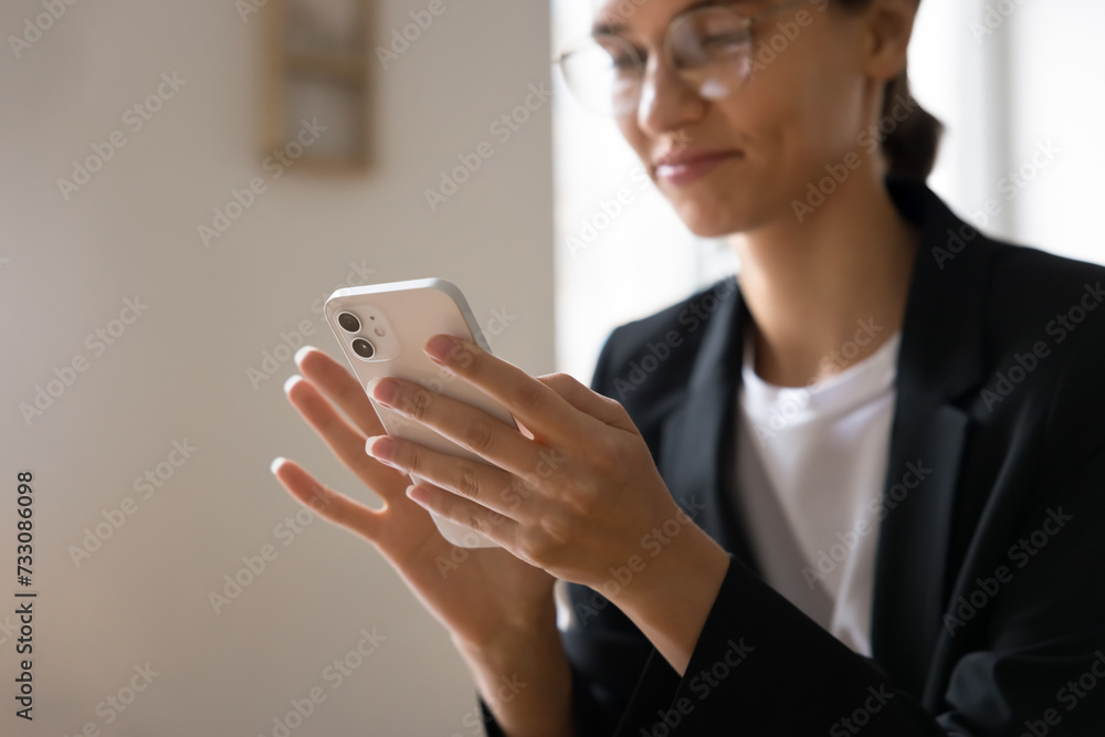 Positive young business professional woman using application on mobile phone, touching screen, typing, looking at screen, smiling, enjoying Internet communication. Close up of hands holding smartphone Positive young business professional woman using application on mobile phone, touching screen, typing, looking at screen, smiling, enjoying Internet communication. Close up of hands holding smartphone