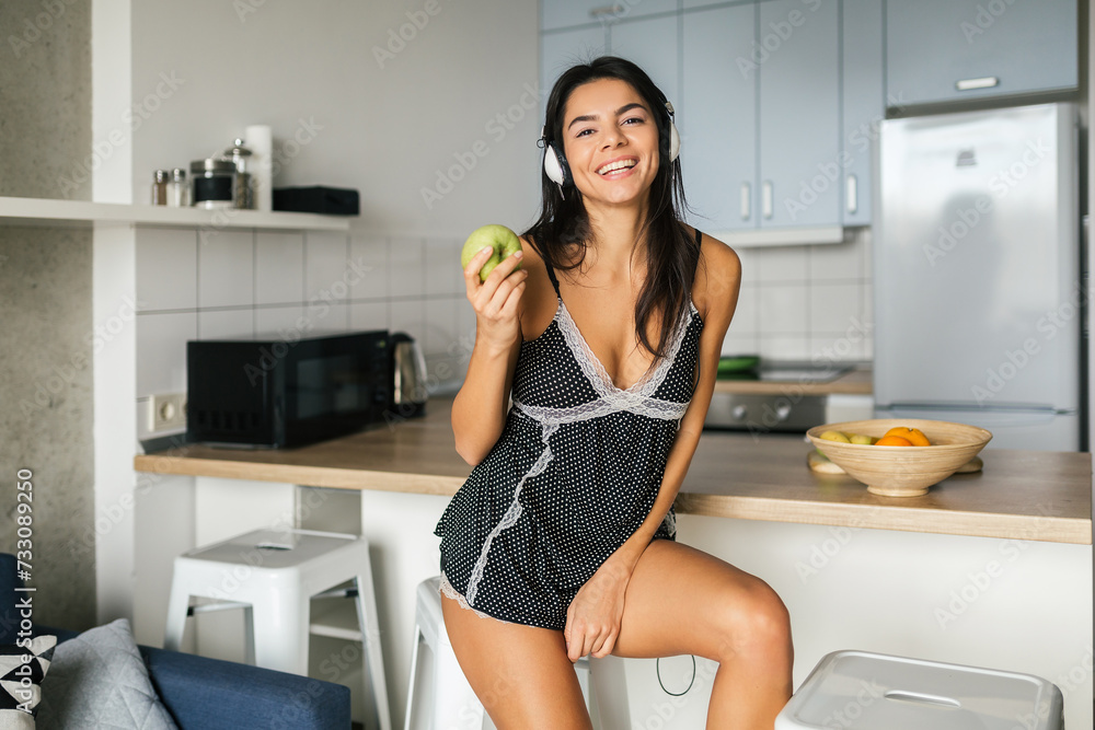 attractive smiling woman in pajamas having breakfast in kitchen attractive smiling woman in pajamas having breakfast in kitchen