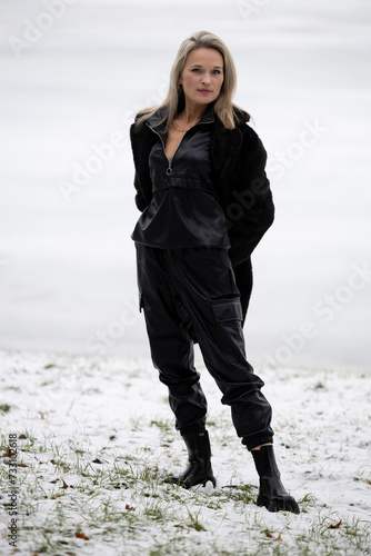 Portrait of a young beautiful woman in black coat on winter nature