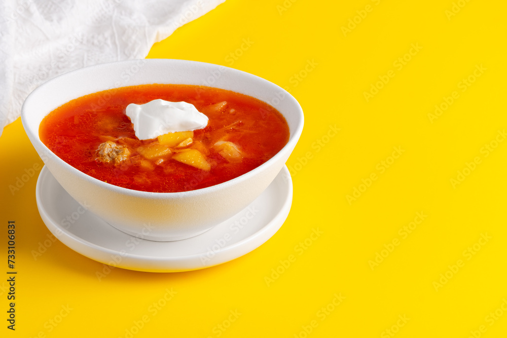 Red borscht in bowl on a yellow background, traditional dish that is cooked with broth. Copy space Red borscht in bowl on a yellow background, traditional dish that is cooked with broth. Copy space