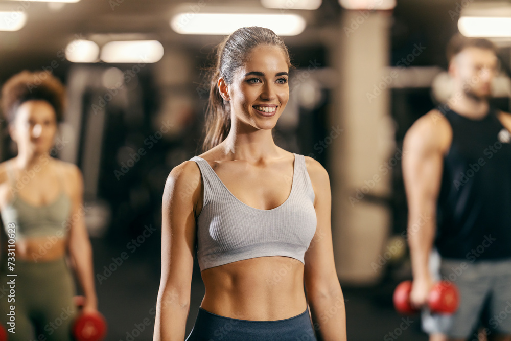 Portrait of a fit sportswoman exercising with friends in a gym.