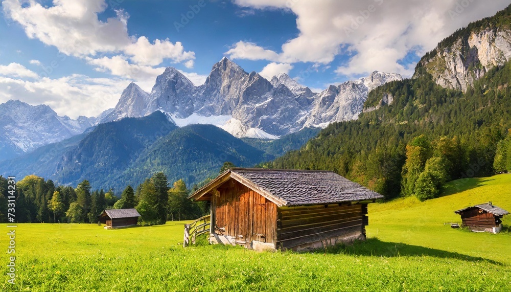 alpine green meadow and wooden barns zugspitze mount in the background garmisch partenkirchen bavaria germany