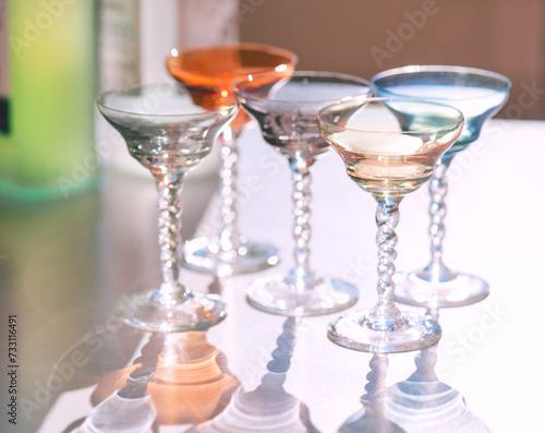 Crystal colorful stemware set with reflection on a table. Colourful elite set of empty alcohol liquor glasses on white, border design. Stemmed glasses, drinkware closeup 