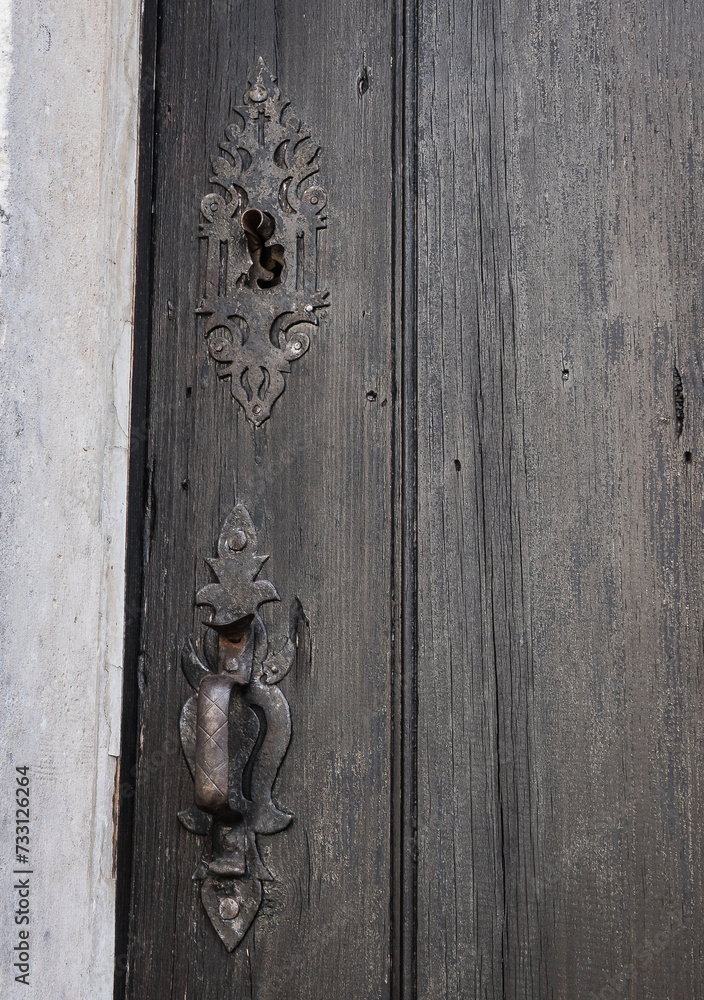 Old decorative doorknob and keyhole trim, aged door boards.