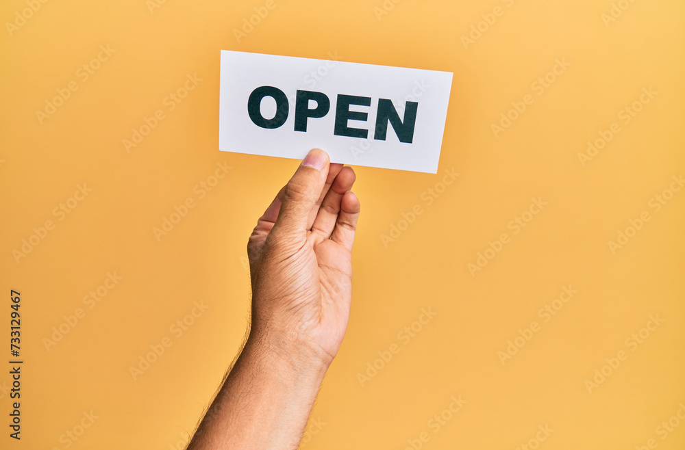 Hand of caucasian man holding paper with open word over isolated yellow background Hand of caucasian man holding paper with open word over isolated yellow background