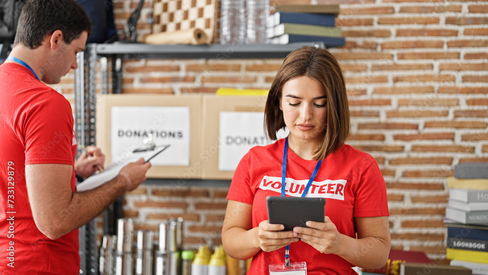 Fototapeta premium Man and woman volunteers using touchpad taking notes working at charity center