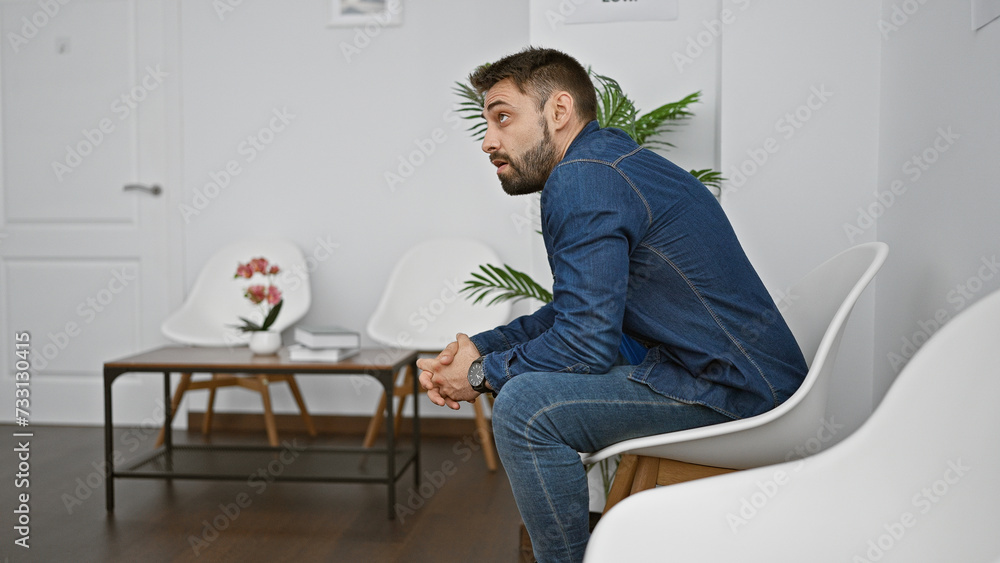 Young hispanic man sitting on chair looking upset at waiting room Young hispanic man sitting on chair looking upset at waiting room