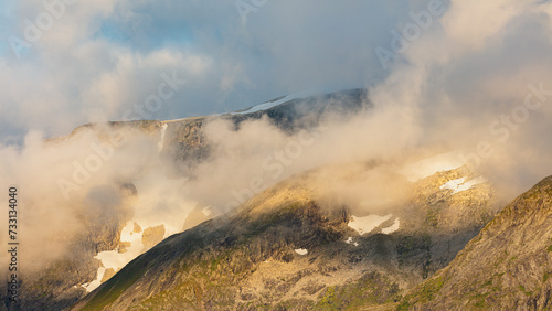 Clouds creeping up a mountain range in west Norway in early morning light 