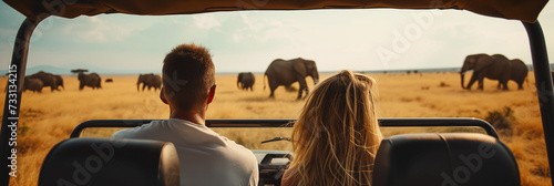 Päarchen sitzt im Auto und beobachtet Elefanten während einer Safaritour in Afrika photo