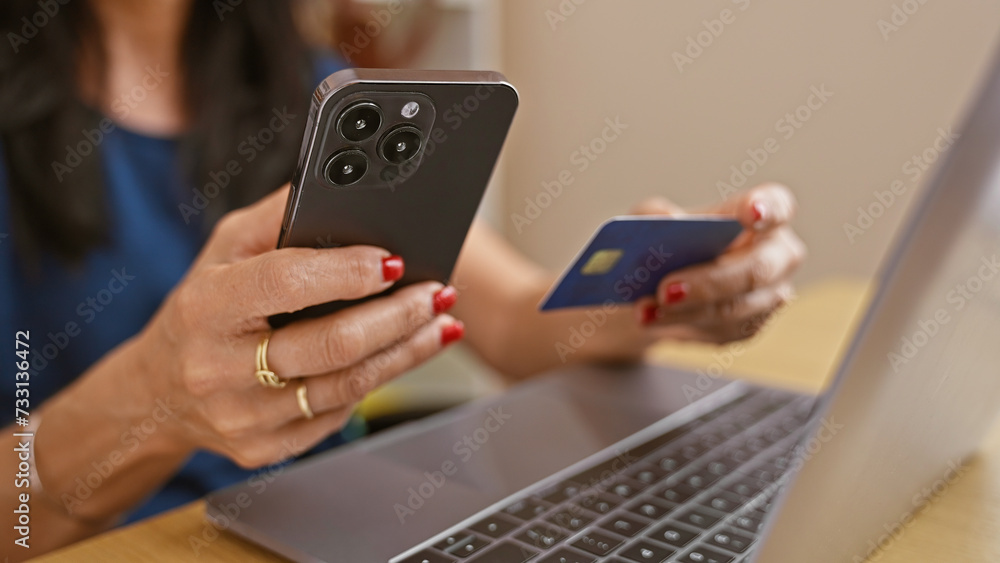A businesswoman makes a secure online payment with her credit card and smartphone at her modern office workspace.