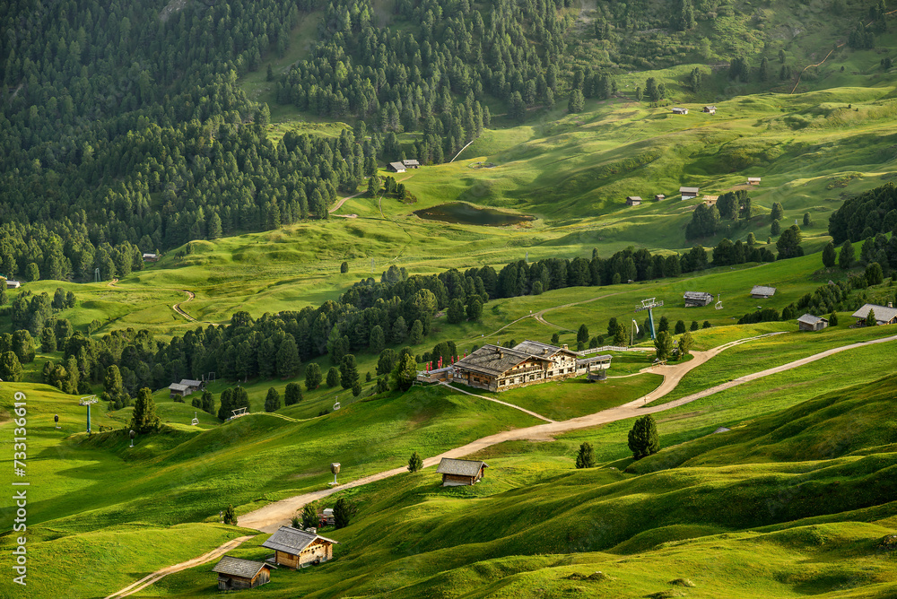 Grassy slopes and alpine huts in the Italian Dolomites during summer.