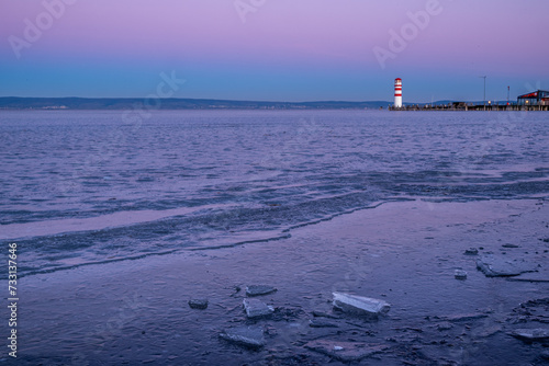 The frozen Neusiedler See with the lighthouse of Podersdorf in the background during a winter dawn in Burgenland, Austria. photo