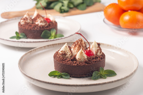 Delicious chocolate tart garnish with cherry and mint. Classic dessert.