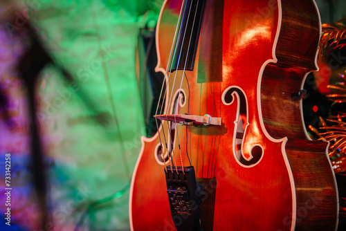 Riga, Latvia - January 18, 2024 - Close-up of a double bass with its curved body, strings, and f-holes, colorful blurred background. photo
