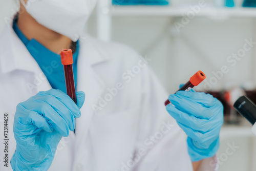 Female doctor taking blood sample tube from shelf with analyzer in lab Technician is holding blood test tubes in the laboratory.