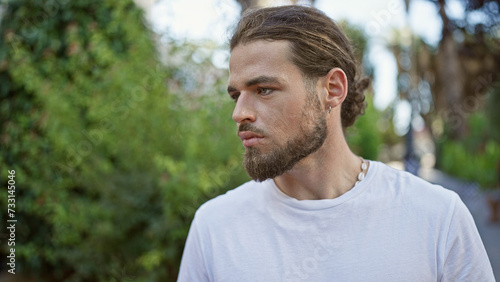 Young hispanic man looking to the side with serious expression at park