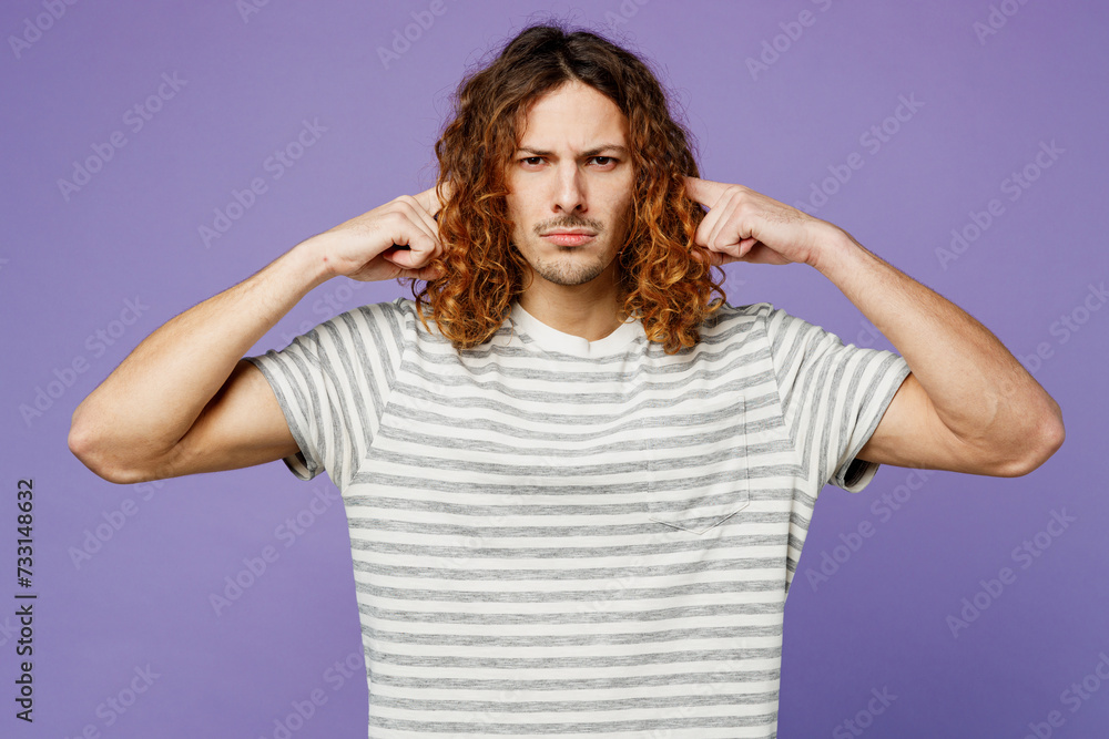Young sad man wears grey striped t-shirt casual clothes cover ears with hands fingers do not want to listen scream isolated on plain pastel light purple background studio portrait. Lifestyle concept. Young sad man wears grey striped t-shirt casual clothes cover ears with hands fingers do not want to listen scream isolated on plain pastel light purple background studio portrait. Lifestyle concept.