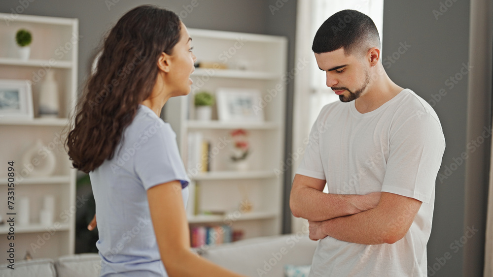 Fototapeta premium Serious argument at home, a beautiful couple locked in disagreement, standing together in their living room showcasing a lifestyle conflict.