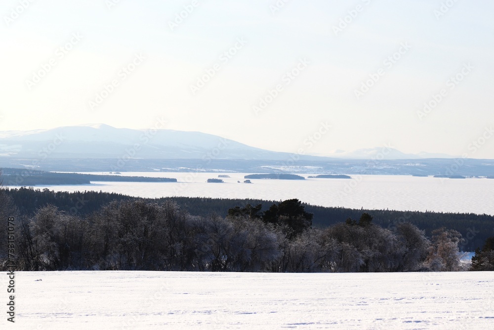 View of the mountains, meadows and the lake. Trees and mountains in winter. Winter landscape in Östersund.

