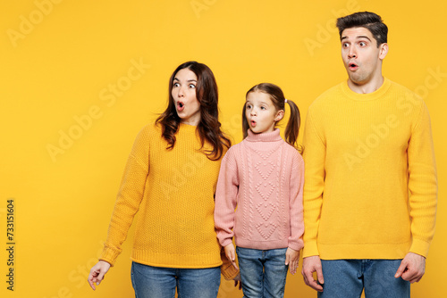 Young shocked scared sad parents mom dad with child kid girl 7-8 years old wear pink knitted sweater casual clothes look aside on area mock up isolated on plain yellow background. Family day concept. photo