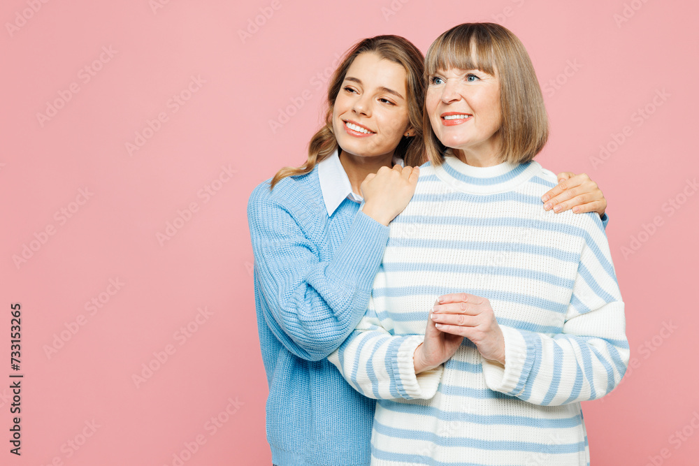 Elder minded parent mom 50s years old with young adult daughter two women together wear blue casual clothes hug look aside on area isolated on plain pastel light pink background. Family day concept. Elder minded parent mom 50s years old with young adult daughter two women together wear blue casual clothes hug look aside on area isolated on plain pastel light pink background. Family day concept.