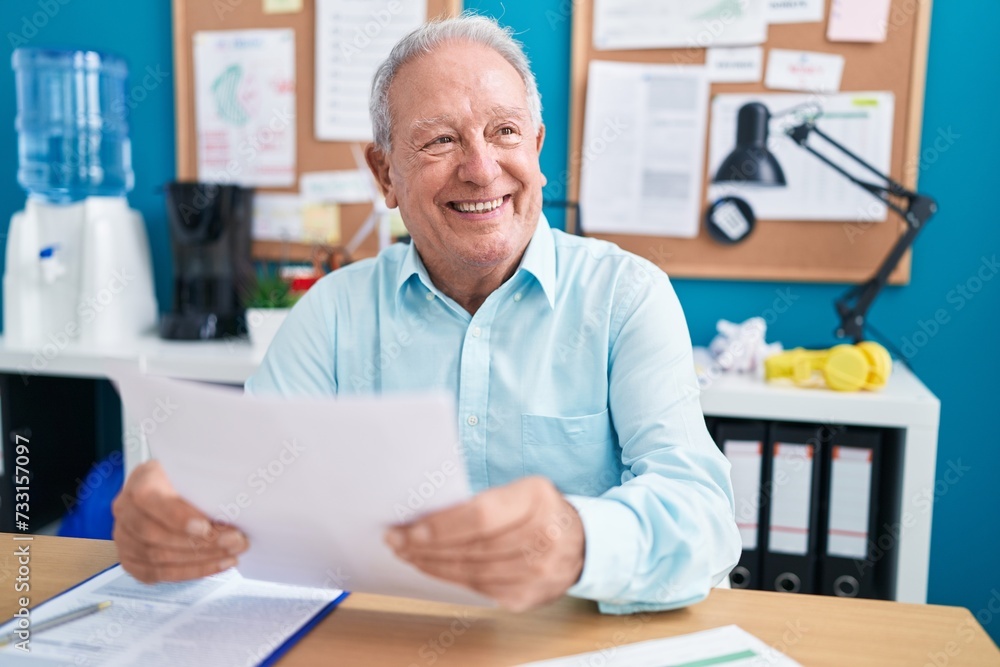Middle age grey-haired man business worker reading document at office Middle age grey-haired man business worker reading document at office