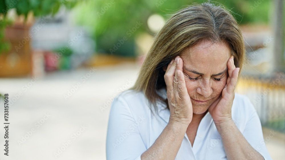 Middle age hispanic woman suffering for headache at park Middle age hispanic woman suffering for headache at park