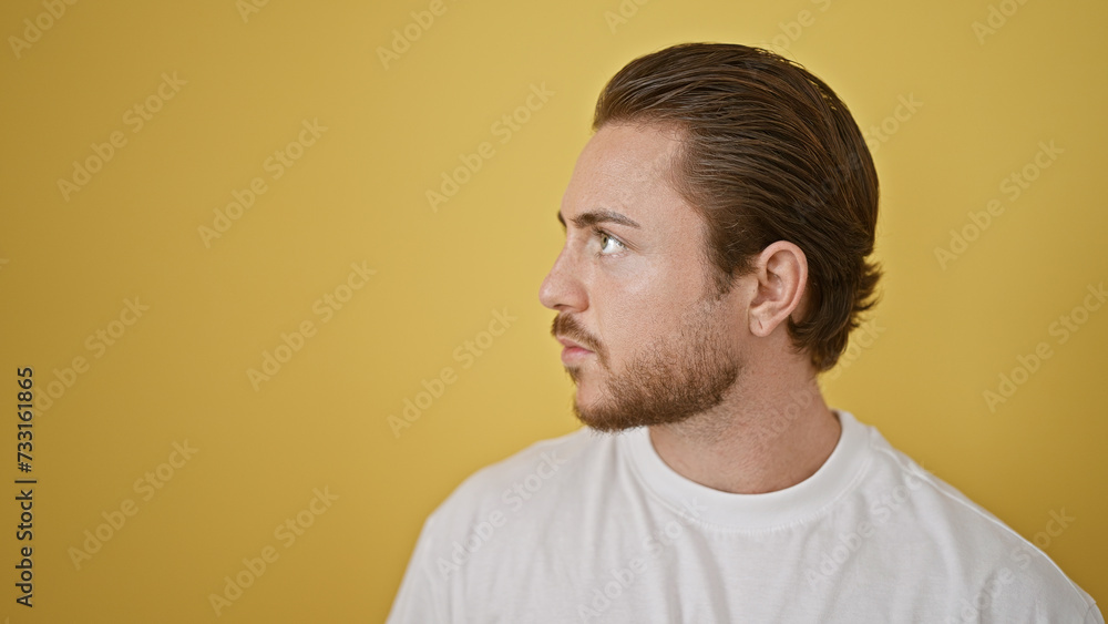 Obraz premium Young hispanic man looking to the side with serious expression over isolated yellow background