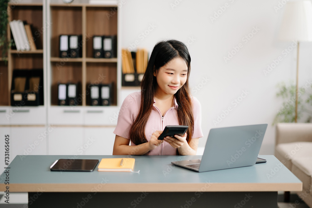 Asian woman sitting at a desk using a laptop computer Navigating Finance and Marketing with Technology Asian woman sitting at a desk using a laptop computer Navigating Finance and Marketing with Technology