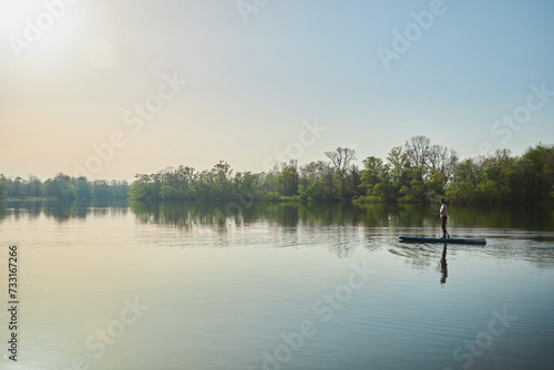 A woman swims on a sapboard on the lake. Water entertainment. photo