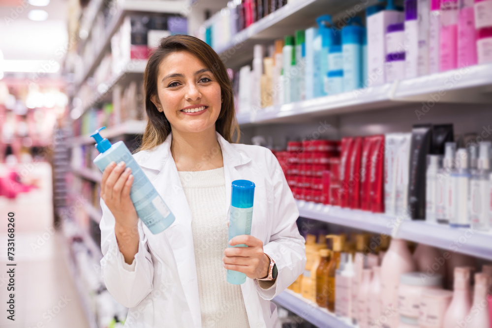 Cheerful saleswoman offering hair care products in cosmetic shop