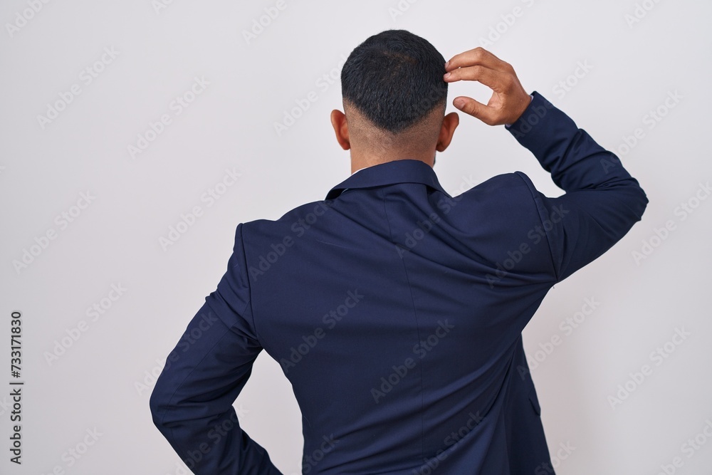 Young hispanic man wearing business suit and tie backwards thinking about doubt with hand on head Young hispanic man wearing business suit and tie backwards thinking about doubt with hand on head
