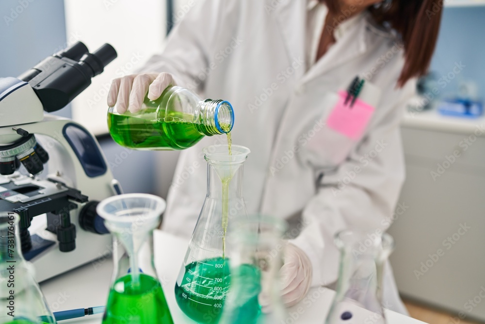 Young beautiful hispanic woman scientist pouring liquid on test tube at laboratory Young beautiful hispanic woman scientist pouring liquid on test tube at laboratory