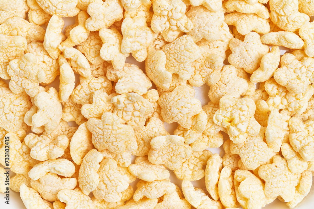 Close-up of numerous crisp rice cereal pieces scattered on a white background. Close-up of numerous crisp rice cereal pieces scattered on a white background.