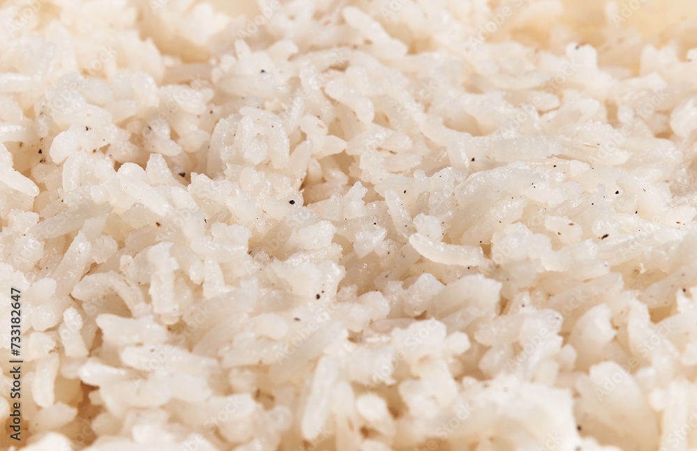 Close-up view of cooked white rice grains seasoned with specks of black pepper, hinting at a simple, staple food. Close-up view of cooked white rice grains seasoned with specks of black pepper, hinting at a simple, staple food.