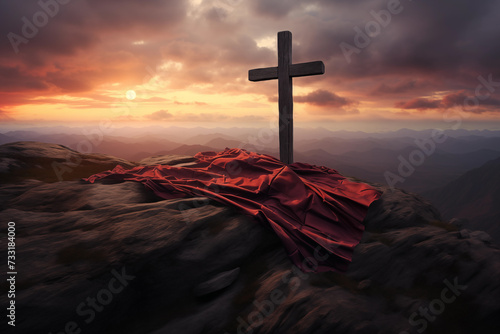 A christian cross with a red cloth, on top of the mountain against sunset light and cloudy sky in a dramatic scenery. Fosus on the crooss photo