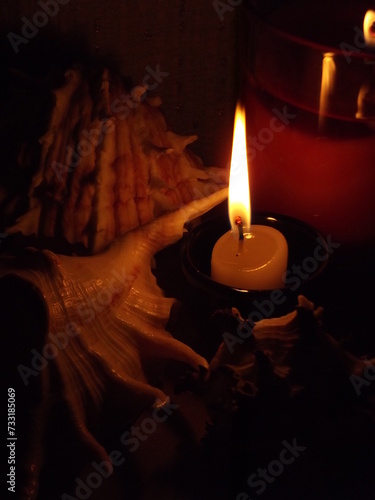 Burning candle and seashells. Vertical orientation.