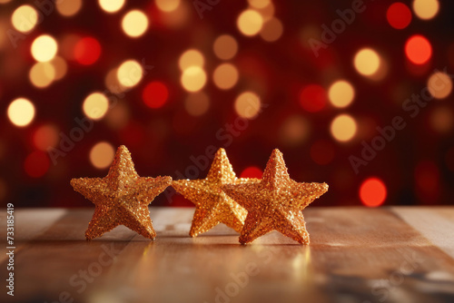 Gold christmas stars with christmas glowing golden red on a red blurred bokeh background.