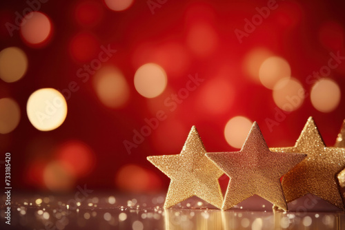 Gold christmas stars with christmas glowing golden red on a red blurred bokeh background. © Wararat