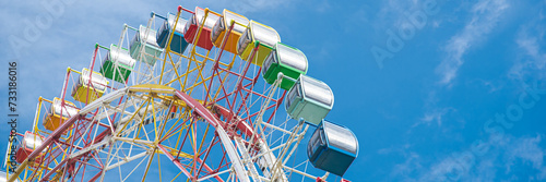 Panorama colorful sightseeing cabin or multiple passengers carrying components with support frame, rim of modern Ferris Wheel at amusement park in Nha Trang, Vietnam, blue sky, spoke cable photo