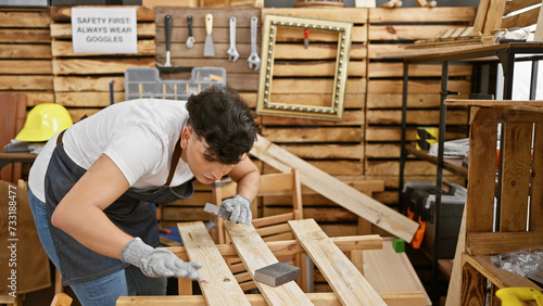 A man engages in woodworking using a sanding block, concentrating in a well-equipped workshop.