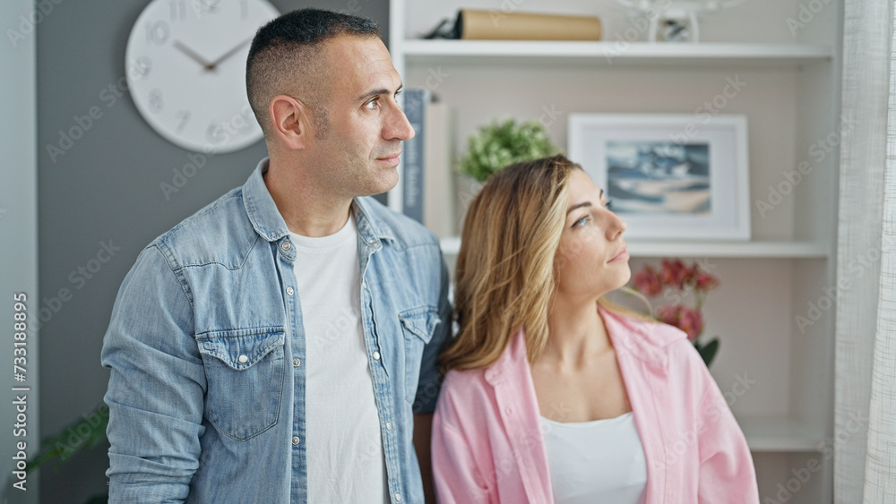 Man and woman couple standing together looking to the side relaxed at home Man and woman couple standing together looking to the side relaxed at home