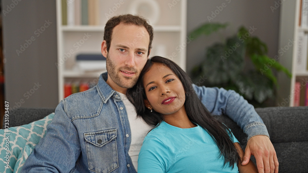 Beautiful couple hugging each other sitting on sofa with relaxed face at home Beautiful couple hugging each other sitting on sofa with relaxed face at home