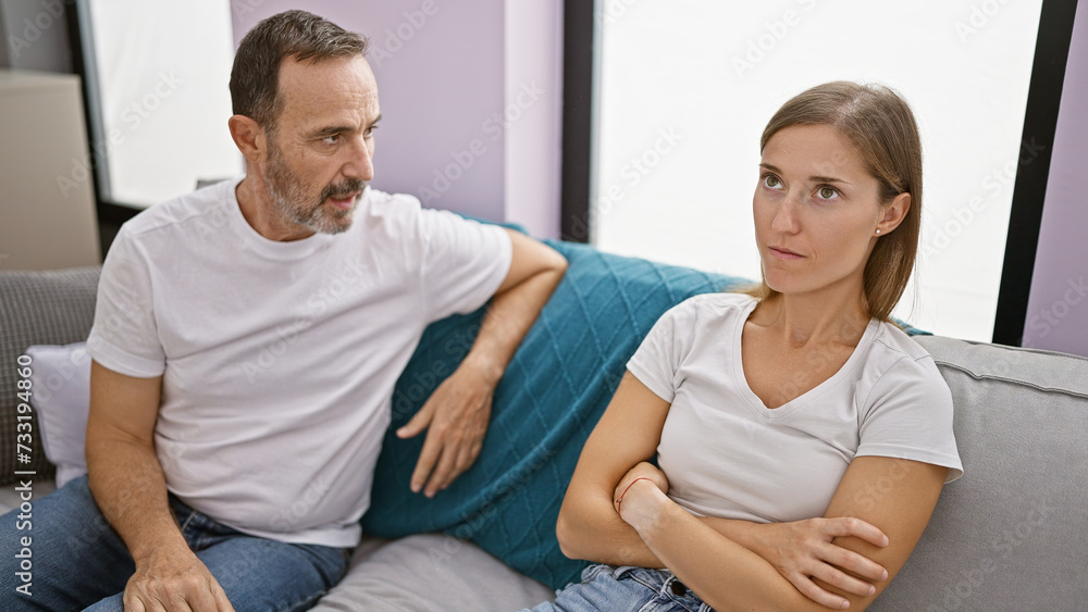 Unhappy father and daughter locked in a heated argument while sitting on the sofa at home, their love stretched thin amid this family disagreement Unhappy father and daughter locked in a heated argument while sitting on the sofa at home, their love stretched thin amid this family disagreement