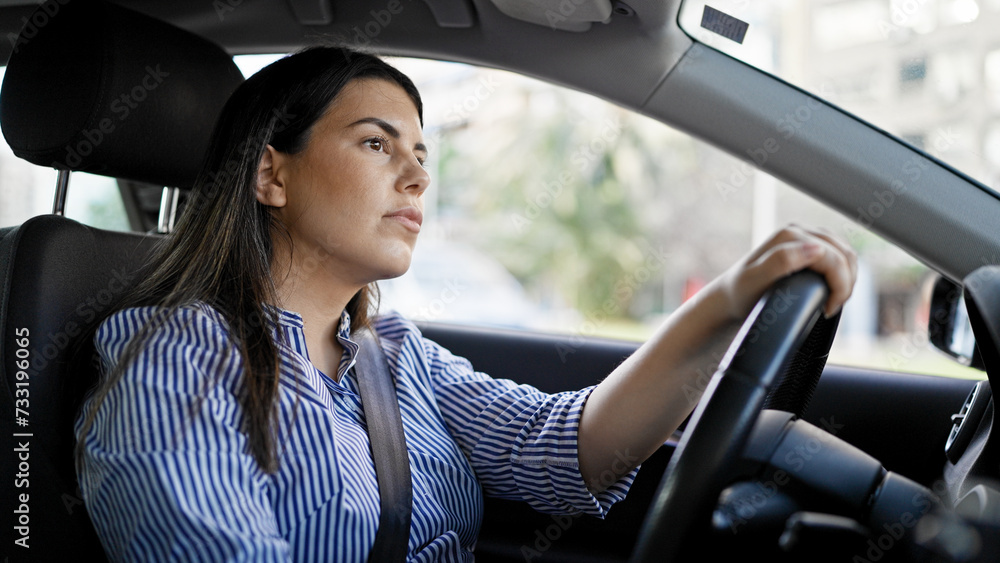 Young beautiful hispanic woman driving a car on the road