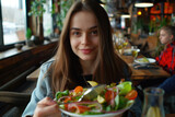 A beautiful girl eating salad in a restaurant. Healthy life eating concept