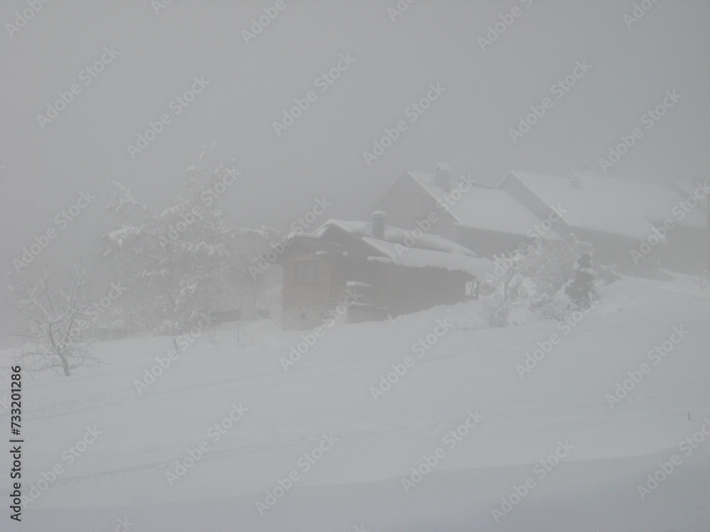 chalets enneigés dans la brume en hiver situés   vallée de Bellevaux dans les Alpes en Haute-Savoie